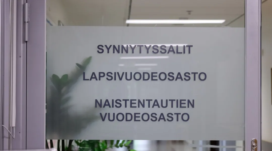 Sairaalan ovessa kyltti, jossa lukee synnytyssalit, lapsivuodeosasto, naistentautien vuodeosasto.