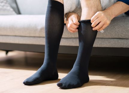 Mies kiskoo kompressiosukkia jalkaansa.